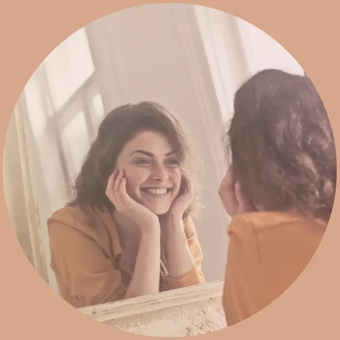 Femme se regardant avec douceur dans un miroir, symbole de reconnexion à soi